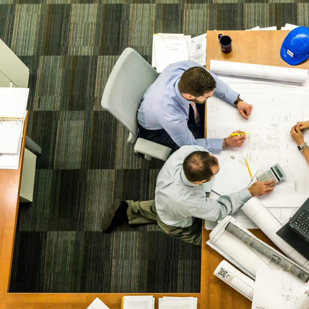 Top view of a team working on construction plans in an office setting.